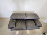 grey leather sofa in a corner of a room with a white wall