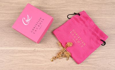 the pink bag is next to a gold cross on a wooden table