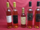 six bottles of wine are lined up in a row on a pink background