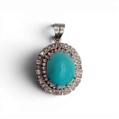 un gros plan d'un pendentif en turquoise et diamants sur fond blanc