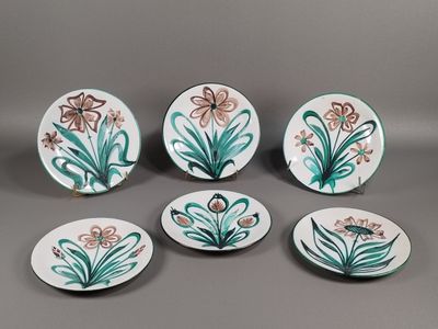 quatre assiettes sur lesquelles sont peints des fleurs et des feuilles sur un fond gris