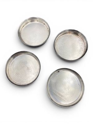 four silver metal trays on a white surface with a white background