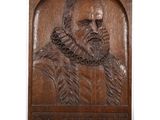 carved wood plaque of a man with a beard and a chain around his neck