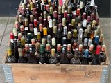 de nombreuses bouteilles de vin dans une caisse en bois posée par terre