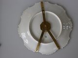 a white plate with a gold clock on top of it