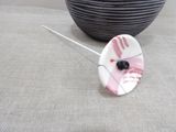a white and pink flower brooch with a black button