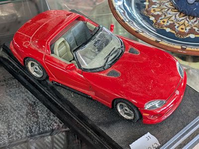 a red toy car on display in a glass case