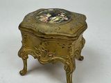 a small gold box with a picture on it
