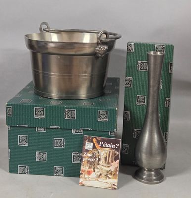 a silver bowl and a silver vase on a stack of green boxes