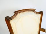 une chaise en bois avec un dossier et des accoudoirs rembourrés de couleur beige