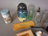 a table with a lot of items on it including a vase, a bottle, a box, a cigarette and a lighter