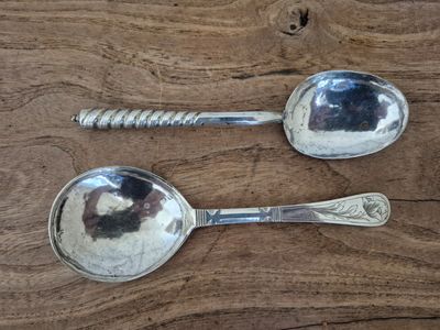 two spoons that are sitting on a wooden table