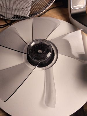 un ventilateur posé sur une table, à côté d'un téléphone portable
