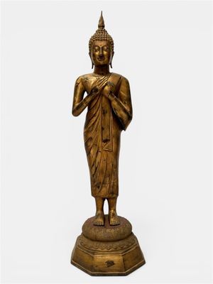 une statue en bronze représentant un Bouddha debout sur un socle