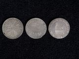 three silver coins sitting on top of a black surface