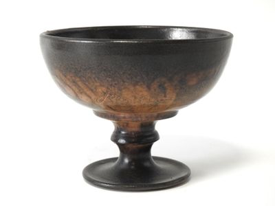 un bol noir et marron posé sur une surface blanche