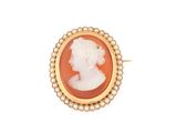 un gros plan sur une broche-camée en or et corail, ornée de perles