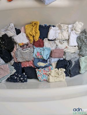 une baignoire remplie de plein de vêtements et d'un ours en peluche