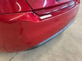 the rear end of a red car with a sticker on it