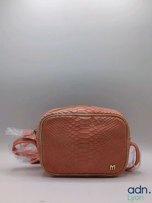 a pink snake skin bag with a white feather on the side