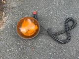une lumière orange posée par terre à côté d'un cordon