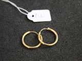 une paire de boucles d'oreilles en or sur une surface noire
