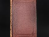 an old book with a brown cover on a black background