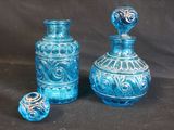 two blue glass vases sitting next to each other on a black background