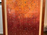 painting of a red and orange abstract painting in a wooden frame on the floor