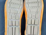 pair of orange and grey shoes with white soles on a blue surface