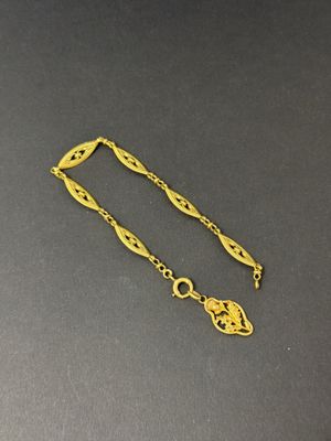 a close up of a gold bracelet with a chain attached to it