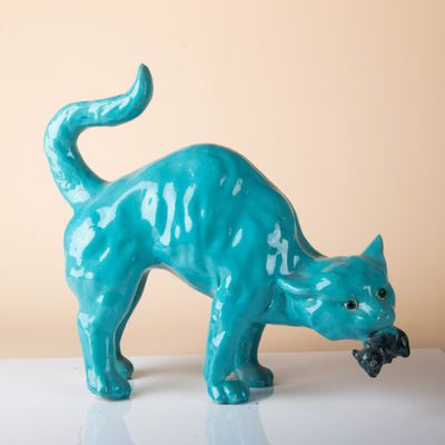 une figurine de chat bleu posée sur une surface blanche