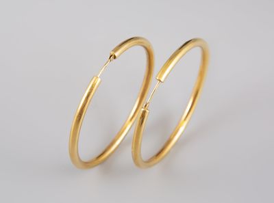 une paire de boucles d'oreilles en or sur fond blanc