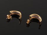 a pair of gold and diamond earrings on a black surface