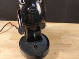 une cafetière noire posée sur une table en bois, avec une clé verte