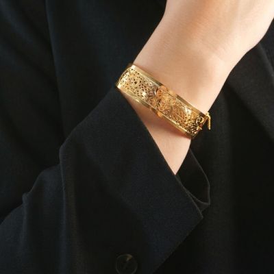 a close up of a person wearing a gold bracelet and a black jacket