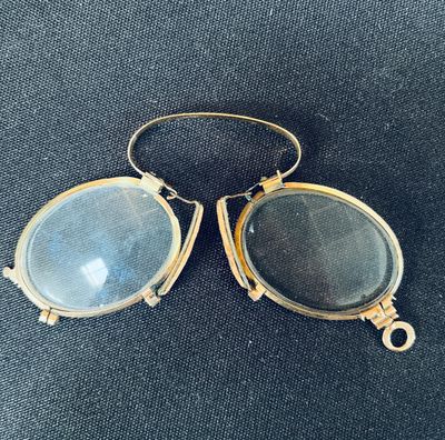 a pair of antique glasses with a gold frame and a blue glass