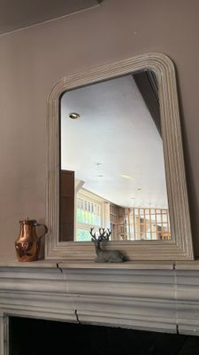 a fireplace with a mirror above it and a vase on top of it