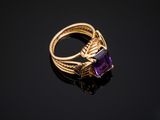a gold ring with an amethorate stone on a black surface