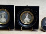 trois portraits miniatures de femmes dans des cadres noirs, posés sur une table
