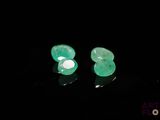 une paire de boucles d'oreilles en émeraude posées sur un fond noir