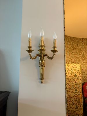 une applique murale sur laquelle sont disposées trois bougies, dans un coin de la pièce