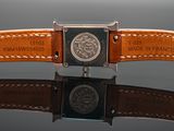 brown leather watch strap with a silver buckle on a black surface