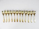 six gold spoons lined up in a row on a white surface