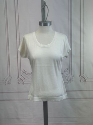 a white shirt on a mannequin stand in front of a wall