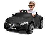 un petit garçon au volant d'une Mercedes de sport noire, portant des lunettes de soleil