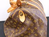 a close up of a brown louis vuitton bag on a black surface