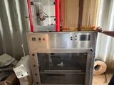 un homme debout devant une machine sur laquelle sont posées des cartons