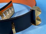 a black belt with gold rivets on it on a blue surface