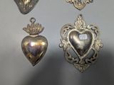 three silver heart shaped ornaments hanging on a wall next to each other